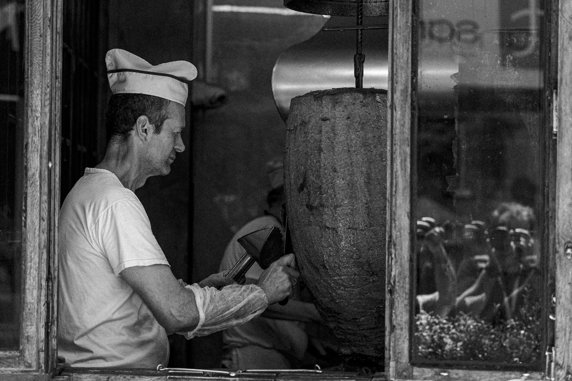 이스탄불의 식당에서 요리사가 이스켄데르 케밥의 재료인 도너 고기를 정성스럽게 썰고 있습니다.