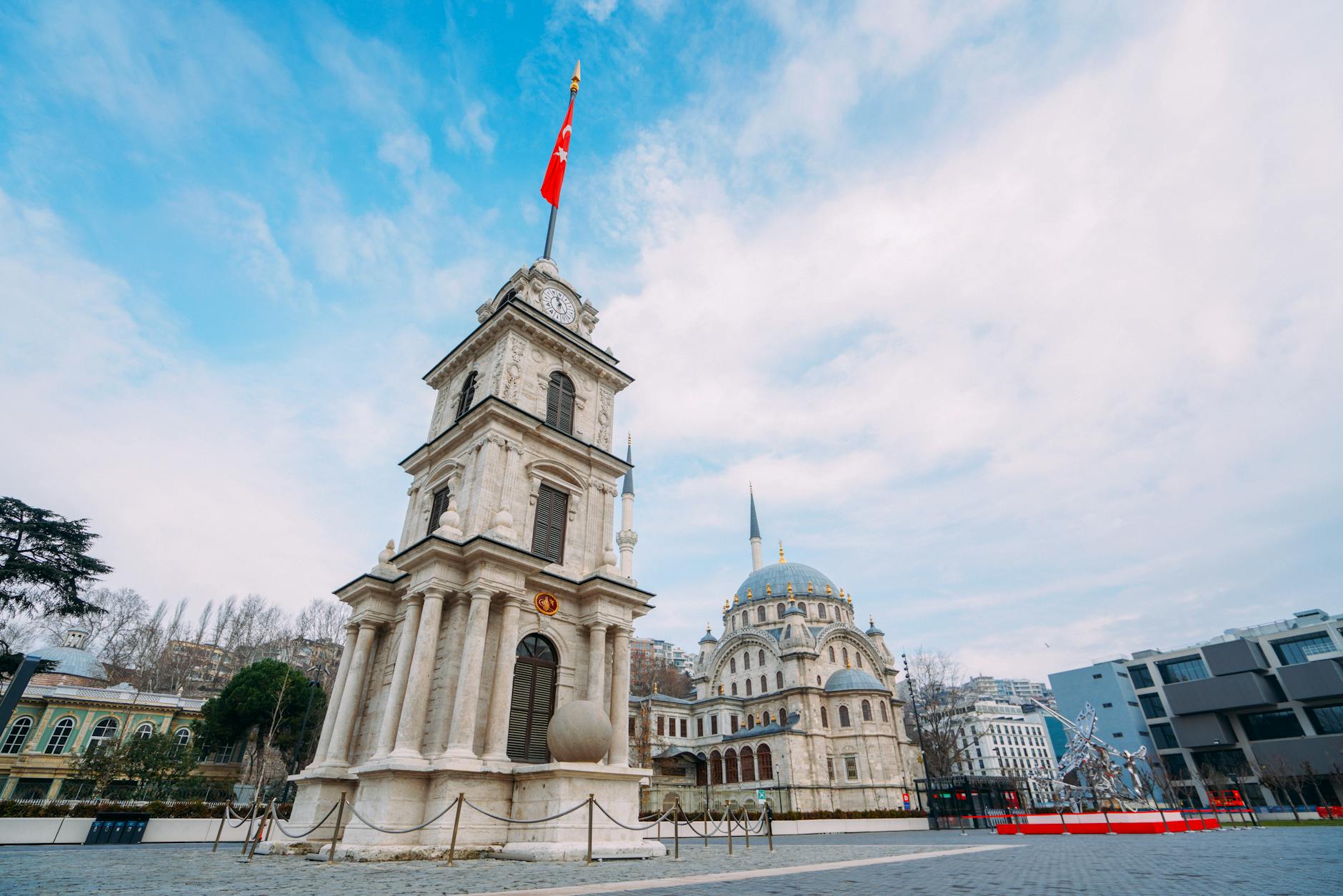 탁 트인 광장에 위치한 토파네 시계탑과 인근의 아름다운 사원 전경.